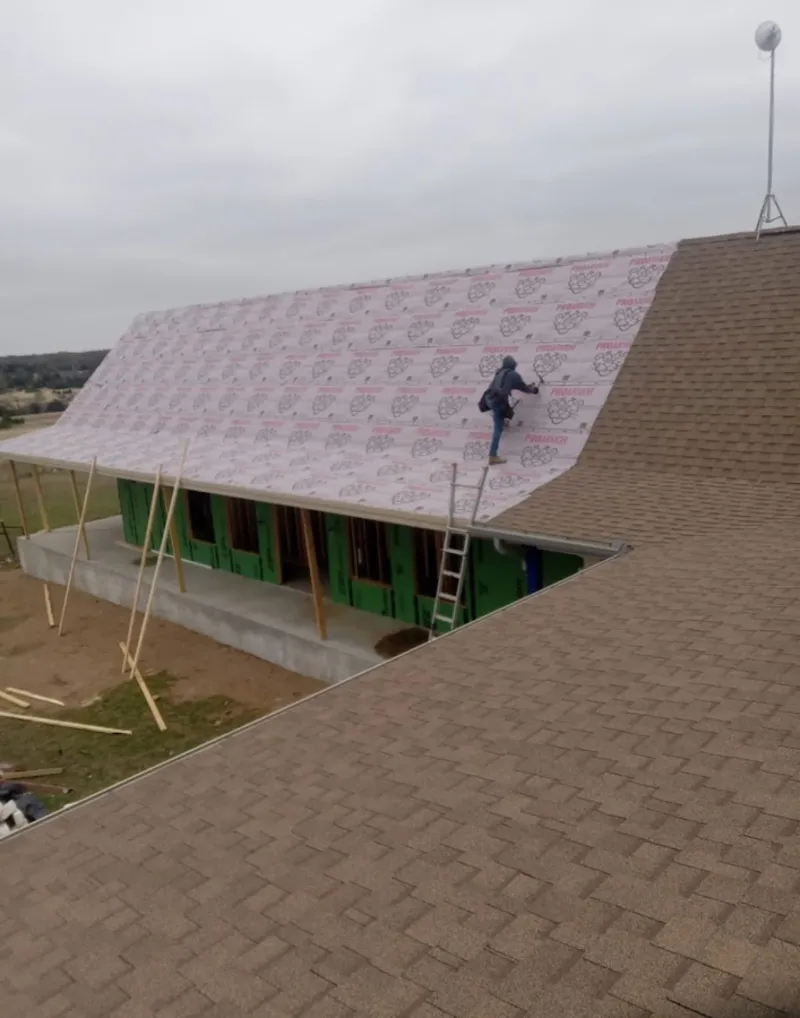Worker preparing underlayment for a metal roof installation in Paw Paw